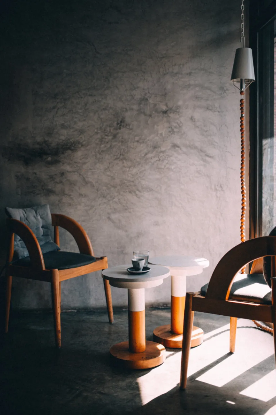 Dos butacas de madera enfrentadas junto a una mesa baja, con luz natural entrando de lado