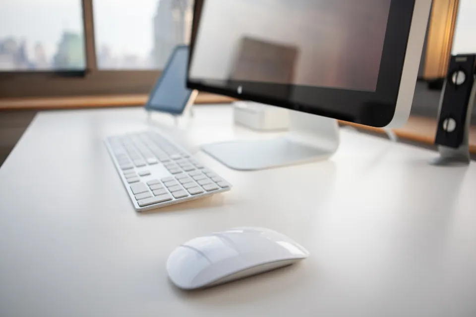 Escritorio despejado con teclado y pantalla junto a una ventana con luz de tarde