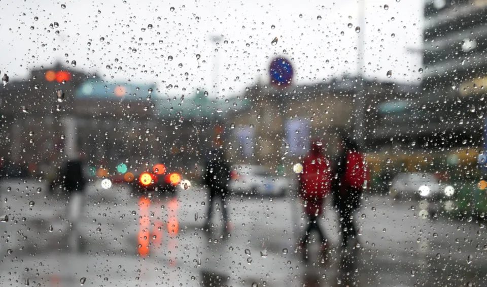 Gotas de lluvia sobre un cristal con una calle desenfocada al fondo